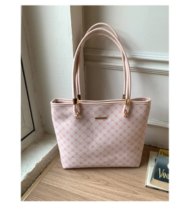 Close-up of pink and white diamond pattern tote bag with gold logo plate detail