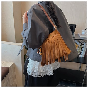 Détail du sac bandoulière en daim marron avec franges, clous étoiles et pendentif perlé