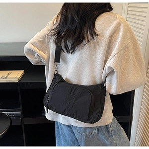 Detail view of black nylon crossbody bag featuring stylish white lettering and adjustable strap