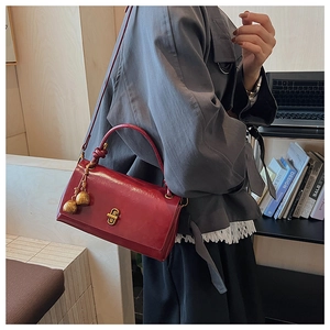 Close-up of a vintage red leather crossbody bag with gold hardware and tassel detail