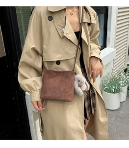 Close-up of brown frosted mini handbag with cute grey rabbit fur ball charm detail