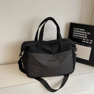 Detail of travel tote bag with black nylon fabric and grey checkered front pocket