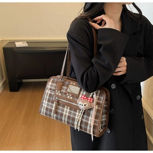 Detail of brown plaid tote bag with faux leather straps and plush bear charm
