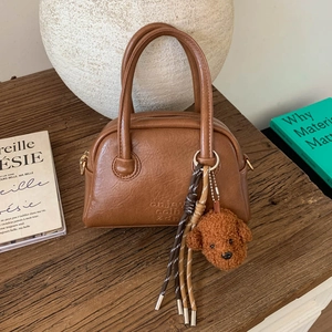 Detail of vintage brown bowling bag with leather texture and cute plush dog charm