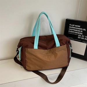 Detail of travel tote bag with brown nylon body and light blue quilted top handles