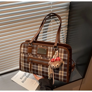 Detail showing vintage plaid tote bag with plush bear charm and metallic zipper