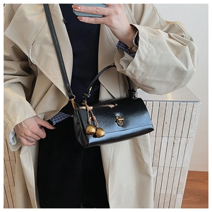 Detail of black wax leather crossbody bag featuring gold twist lock and ball charms
