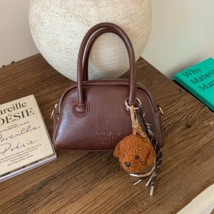Close-up of retro brown bowling bag with embossed letters and a cute plush dog charm