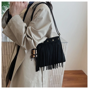 Détail du sac bandoulière bohème noir avec clous étoiles et pompons en perles de bois