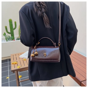 Detail of vintage dark brown faux leather crossbody bag with golden twist lock and charm