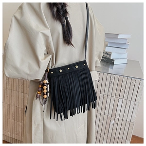 Détail du sac bandoulière bohème en daim noir avec clous étoiles et pompon décoratif