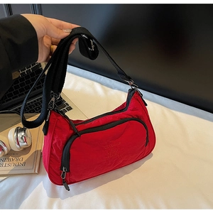 Detail of red nylon crescent bag with adjustable strap and designer text embroidery