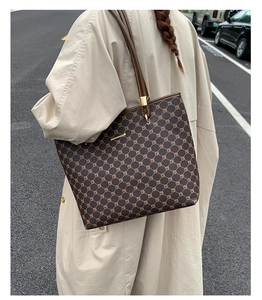 Detail of vintage tote bag with geometric pattern and brown leather handle on model