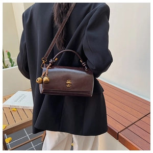 Detail of vintage brown leather handbag with gold twist lock and bell charm detail