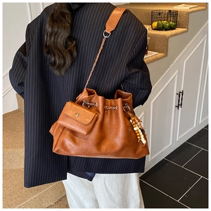 Detail of a brown leather hobo bag with wood bead tassel and mini pouch hanging accessory