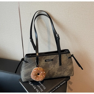 Borsa a spalla grigia con coulisse e ciondolo a forma di ciambella peluche su un libro