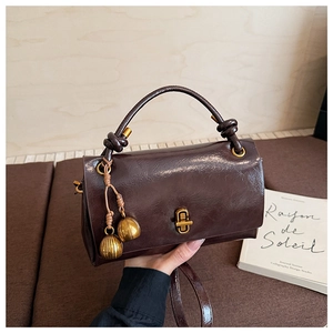 Detailed close-up of dark brown vintage faux leather handbag with a gold twist lock clasp
