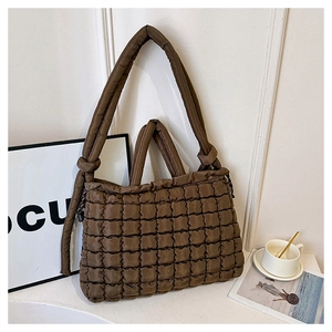 Detail of a brown quilted bubble tote bag with knot handles on a minimal white background