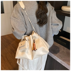 Detail of white drawstring bucket bag with textured leather and decorative colorful beads