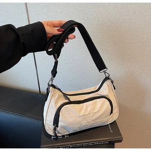 Close-up of beige nylon crescent bag featuring BIFW print and black adjustable strap