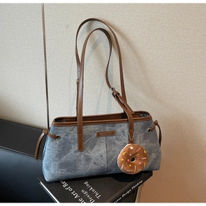 Dettaglio borsa a tracolla in pelle scamosciata blu con tracolla marrone e charm donut