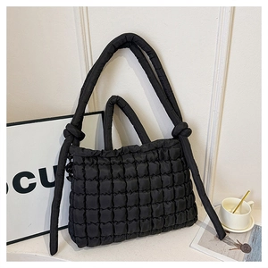 Detailed view of the black quilted bubble fabric tote bag featuring decorative knot handles