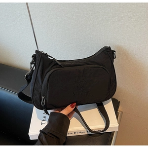 Detail of black crossbody bag with BIFW lettering on matte nylon fabric surface