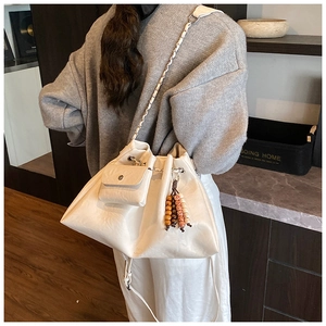 Detail of soft beige hobo bag with cloud pleats, wooden bead charm and chain strap