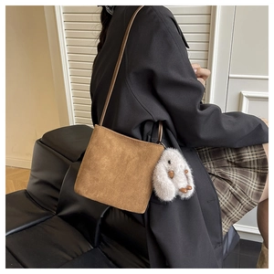 Détail du sac à main en daim marron givré avec un joli pendentif lapin en peluche blanc