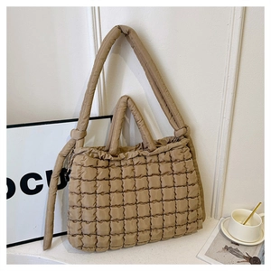 Detail of khaki quilted puffer tote bag featuring soft padded texture and dual straps