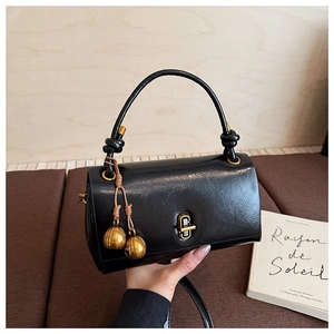Detail of vintage black leather handbag featuring gold ball charms and knot handle