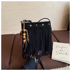 Détail du sac bandoulière en daim noir avec pompons, étoiles dorées et perles boho