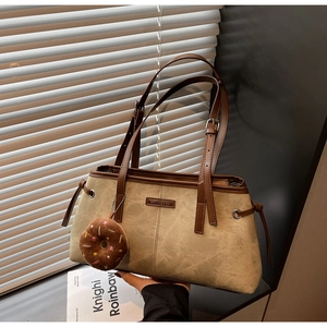 Dettaglio della borsa tote in pelle scamosciata kaki con finiture in pelle e ciondolo donut