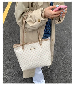 Chic tote bag detail showing khaki leather straps and monogram texture in street setting