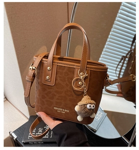 Détail du sac seau à motif léopard avec poignées en cuir et joli pendentif peluche