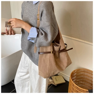 Detail view of large brown suede tote bag with leather straps and gold buckle accents