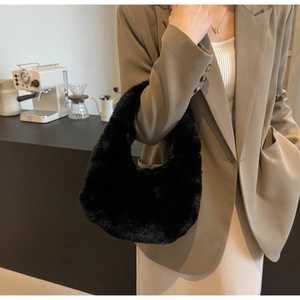Détail d'un sac à main noir en peluche porté avec un blazer kaki pour un style d'automne