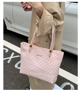 Detail view of pink patterned tote bag with gold hardware held by a model outdoors