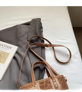 Détail d'un sac seau vintage marron avec doubles poignées et bandoulière réglable