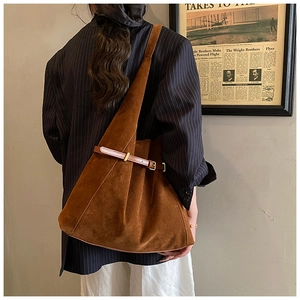 Detail of a large brown suede tote bag styled with a retro blazer in a vintage setting