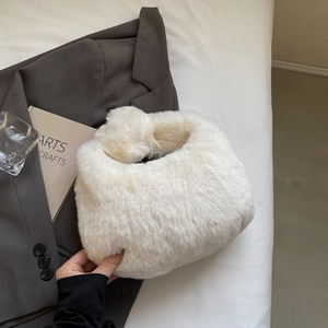 Détail d'un sac à main en peluche blanche sur une veste grise avec décor stylé