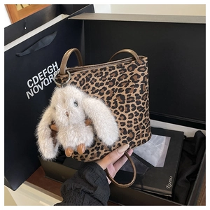 Detail of leopard print tote bag with soft plush rabbit charm and thin round handle