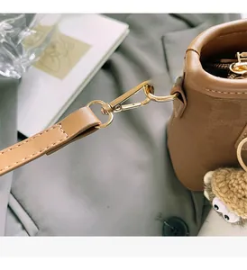 Détails des crochets dorés et du pendentif hibou sur un sac seau marron chic