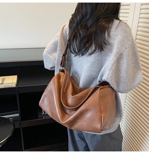 Gros plan sur la texture en cuir marron souple et le profil latéral spacieux du sac à bandoulière