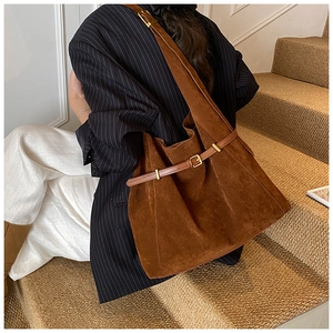 Detail of a large brown suede tote bag with a golden buckle on a vintage strap
