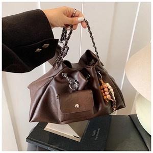 Detailed macro view of dark brown pleated leather bag with chain and beaded charm