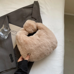 Détail d'un sac à main beige en peluche avec poignée nouée sur un fond de tissu doux