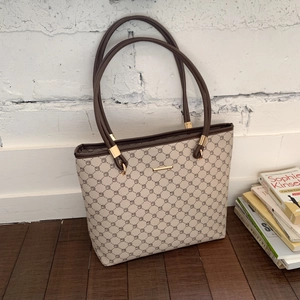 Detail of classic tote bag with geometric pattern and brown leather straps on wood floor