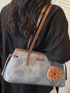 Borsa a spalla in denim blu con finiture in pelle marrone e un ciondolo a ciambella marrone