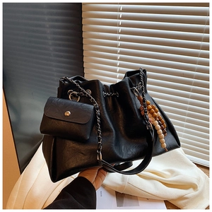 Detail of black drawstring bucket bag with wooden bead decor and silver chain strap